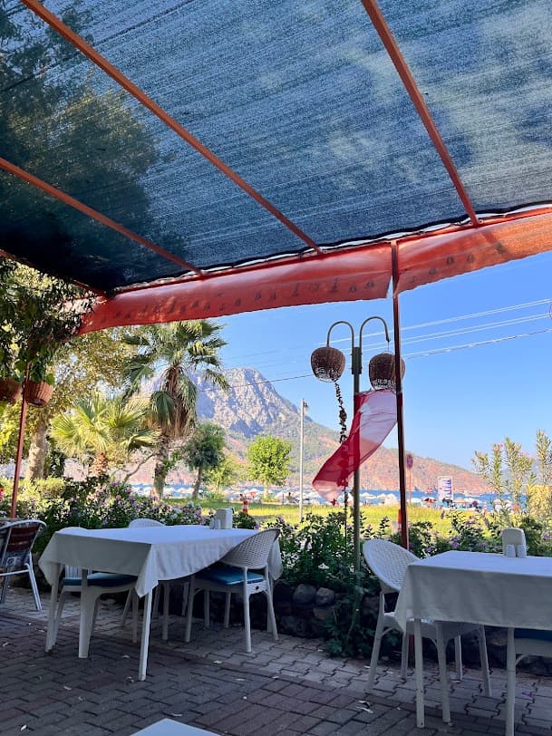 Kaptan Otel Restoran'ın bahçesindeki gölgeli masalardan Adrasan koyu ve dağ manzarası